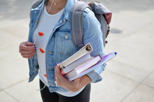 Female student wearing a backpack and carrying textbooks